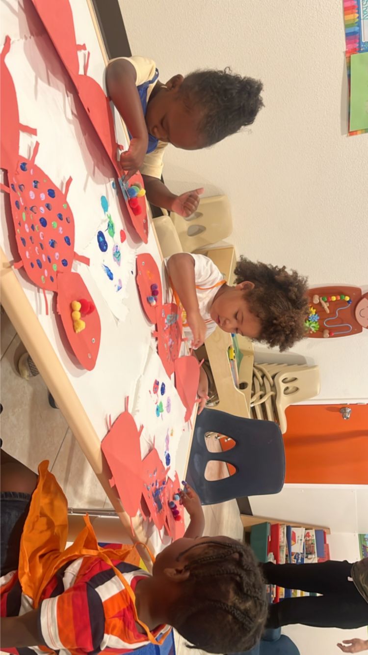 Toddlers at Christian childcare in Las Vegas creating colorful ladybug-themed crafts at a table.