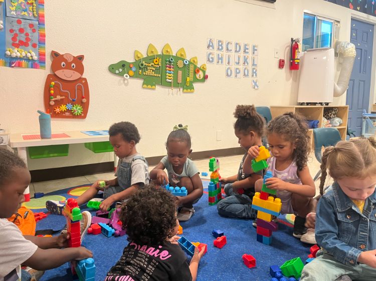 Group of children at a Christian daycare in Las Vegas playing together with colorful blocks on a carpet.