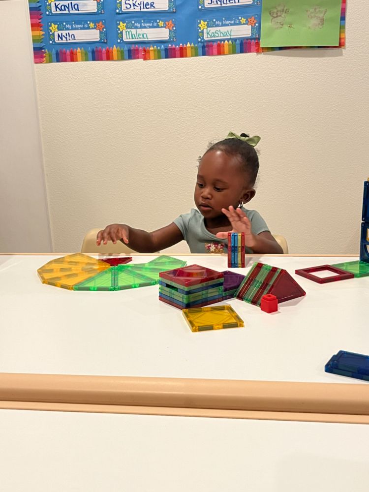 Young girl building with colorful magnetic tiles in a Las Vegas Christian daycare classroom.