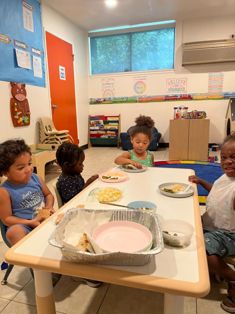 Toddlers enjoying lunch at a shared table inside a Christian daycare center classroom in Las Vegas.